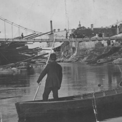 Skats uz trosēs iekārto “Sapieru tiltu” no Mazās Baznīcas (tagad – Strautnieku) ielas gala. Pāri tiltam brauc vieglā automašīna. Iespējams, ka fotografēts atjaunotā tilta atklāšanas dienā – 30.07.1928.