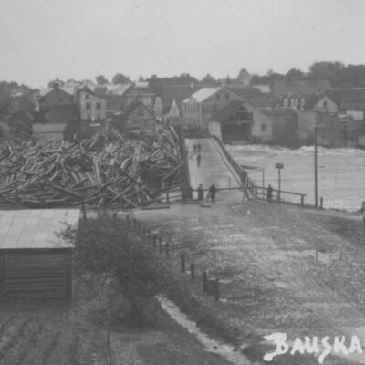 Bauskas panorāma ar daļēji sagrauto tiltu un ebreju lūgšanu namu 22.06.1928. Citas attēlā redzamās ēkas vēl nav redzami cietušas. Labajā pusē - daļa no Ragu kroga. Tagad šīs ēkas adrese ir Dārznieku ceļš 2.